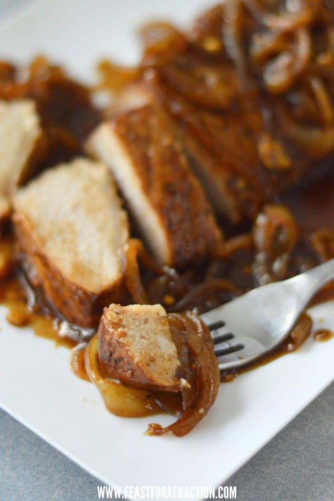 Pork loin roast with caramelized onions on a white plate.