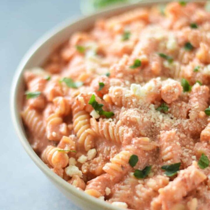 tan bowl filled with cottage cheese pasta garnished with parmesan cheese and parsley