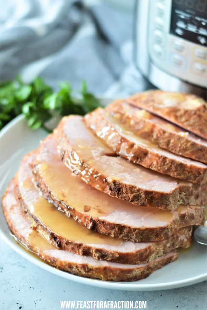 boneless ham sliced on white plate with glaze and instant pot pressure cooker in background