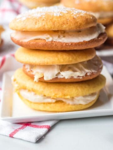 A stack of cream-filled pineapple whoopie pies on a white plate.