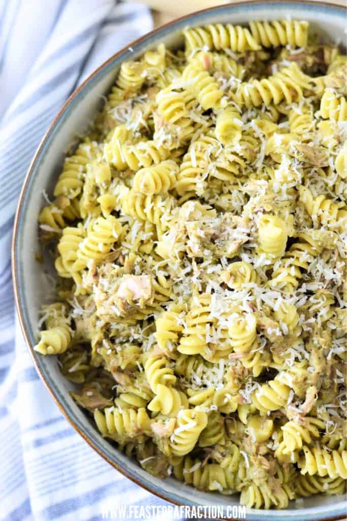 A bowl of rotini pasta mixed with tuna and pesto viewed from above.