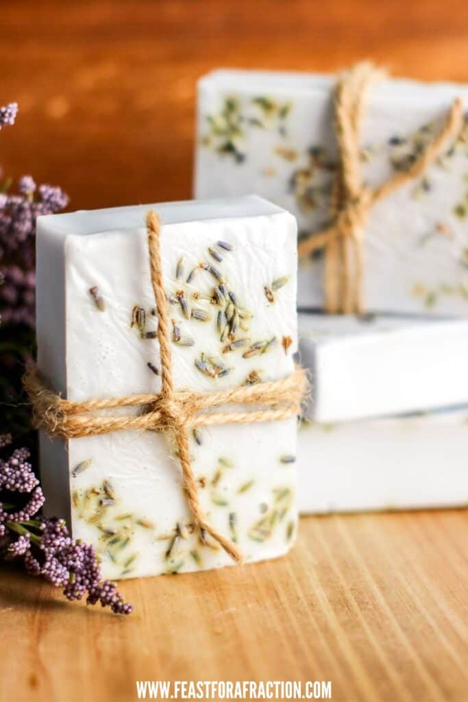 Handmade soap bars with lavender inclusions, tied with twine, on a wooden surface.