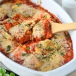 lasagna casserole in white baking dish with wooden spoon