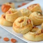 square image of pepperoni pizza pinwheels on white square plate